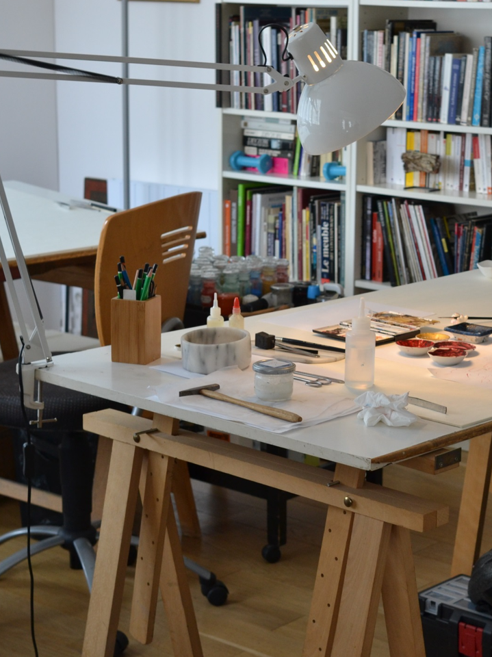 A conservation studio space with paints and brushes laid out on the bench top.